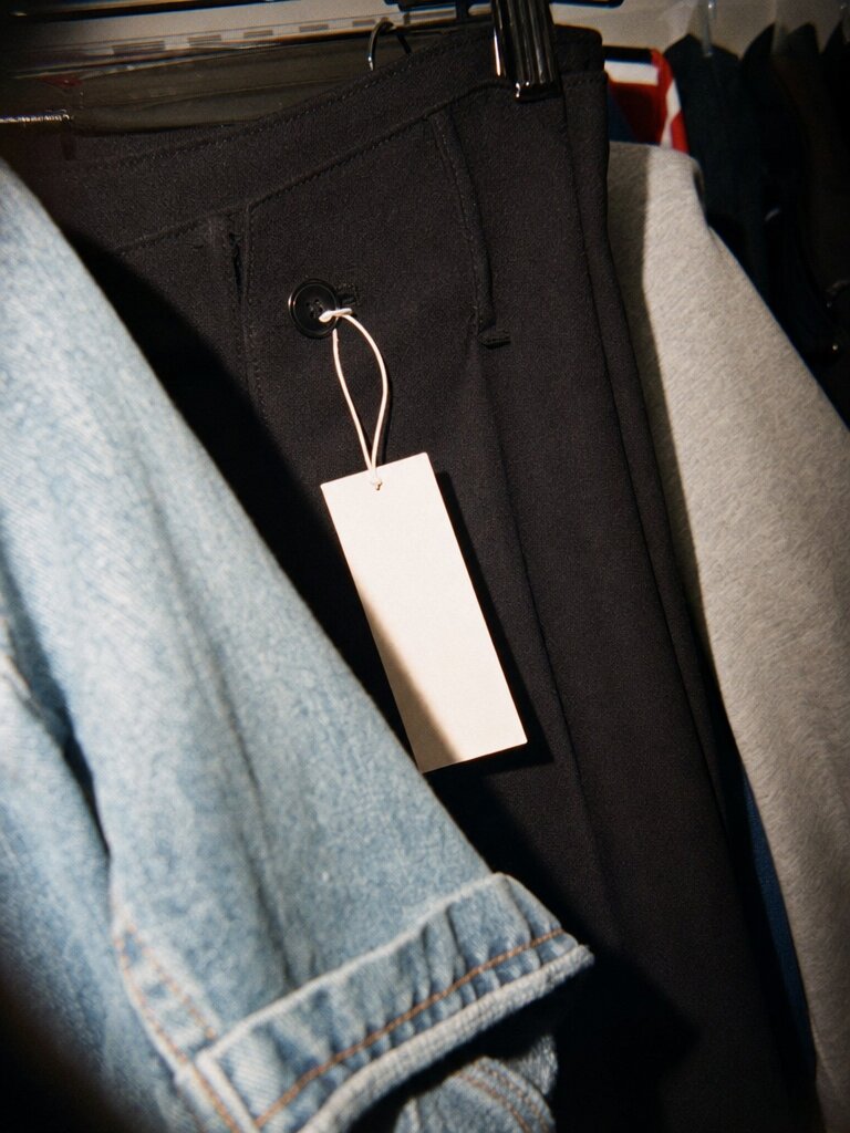 Preisetikett hängt noch an einer dunklen Hose im Schrank